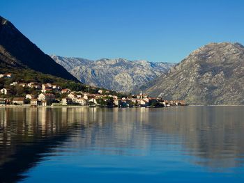 Scenic view of lake and mountains against clear blue sky