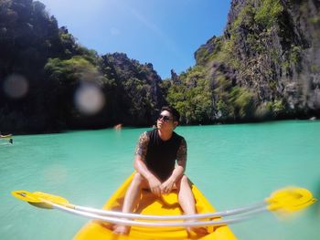 Young man in boat on sea against mountain