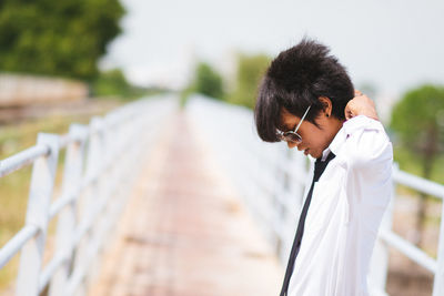 Businessman adjusting shirt while standing on footbridge