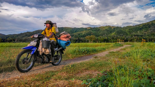 Man riding motorcycle on field against sky