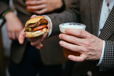 Close-up of man holding burger and beer