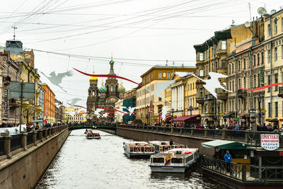 Sailboats in river amidst buildings in city against sky