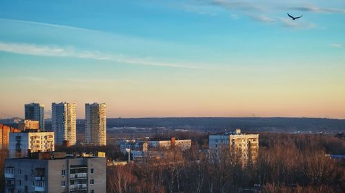 High angle view of buildings against sky during sunset. bird starts fly above city.