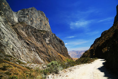 Road amidst mountains against blue sky 