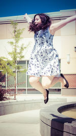 Cheerful teenage girl jumping against building