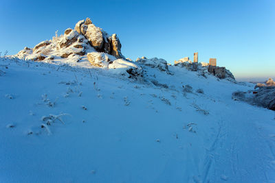 Scenic view of snow covered land against clear blue sky