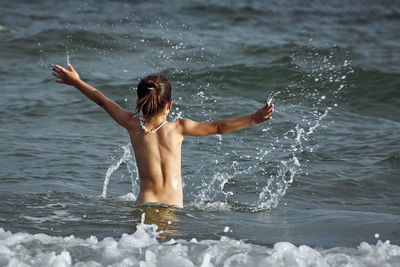 Rear view of woman jumping in sea