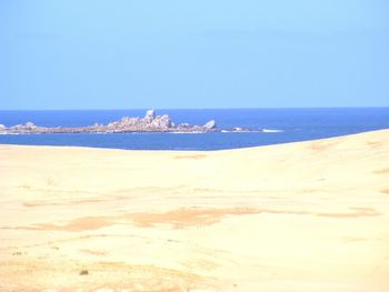 Scenic view of beach against clear blue sky