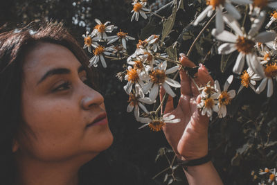 Close-up portrait of young woman with flowers on leaves