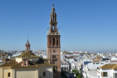 Buildings in city against clear blue sky