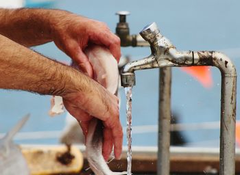 Close-up of cropped hand holding object over white background