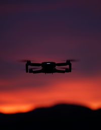 Silhouette airplane flying against sky during sunset