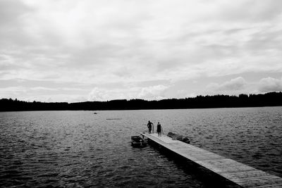 Two people on wooden jetty over lake