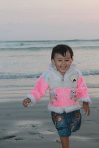 Cheerful girl running at beach during sunset