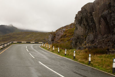 Road leading towards mountains against sky