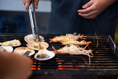 Midsection of person preparing food on barbecue grill