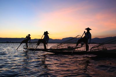 Silhouette people on boat against sea during sunset