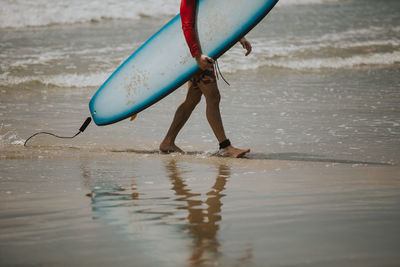 Low section of man jumping on beach