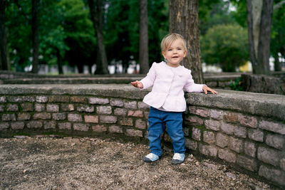 Happy boy standing on stone wall