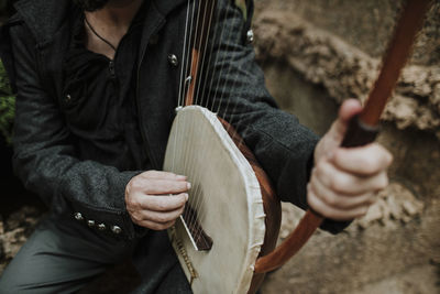 Male playing lyra musical instrument while sitting in park