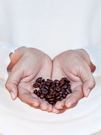 Close-up of human hands holding roasted coffee beans