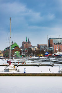 Sailboats in city against sky during winter
