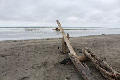 Wooden posts on beach against sky