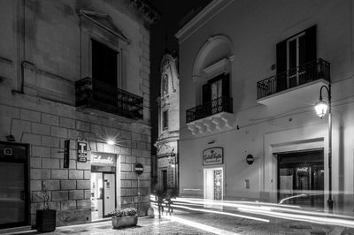 Illuminated street amidst buildings in city at night