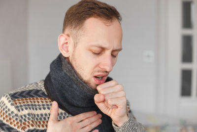 Man gesturing while coughing at home