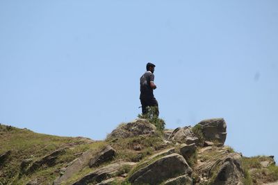 Low angle view of man standing on rock against sky