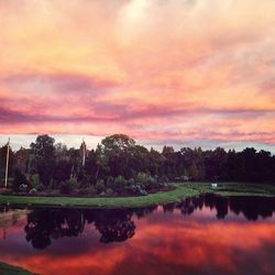 Scenic view of lake against cloudy sky at sunset