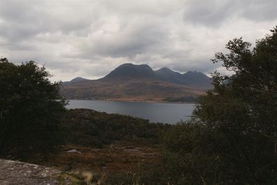 Scenic view of lake and mountains against cloudy sky