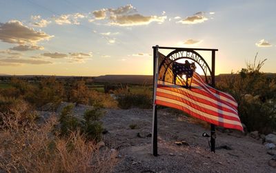 Scenic view of flag against sky during sunset