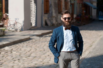 Portrait of young man standing against building