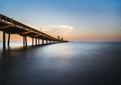 Pier over sea against sky during sunset