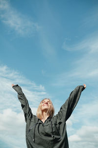 Low angle view of man with arms raised against sky