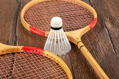 White shuttlecock for badminton between wooden badminton rackets on a wooden background.