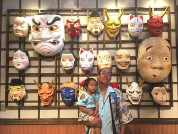 Portrait of father holding cute baby daughter while standing against masks