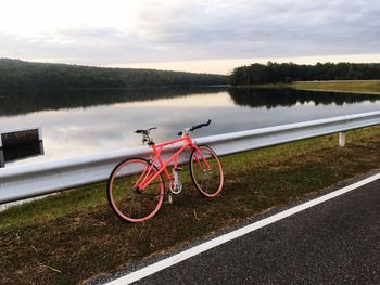 Bicycle on road by lake against sky