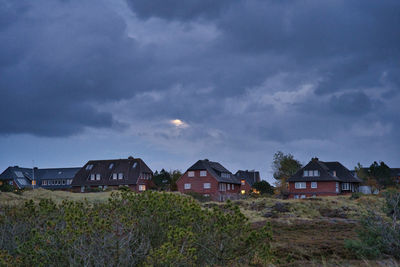 Houses on field by buildings against sky