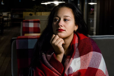 Young woman wrapped in blanket sitting at restaurant