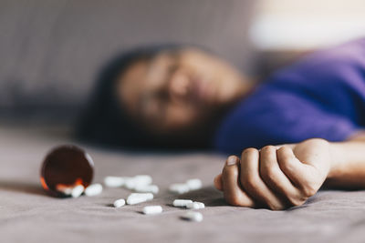 Close-up of pills with woman lying and attempting suicide on floor