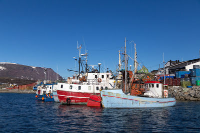 Sailboats moored on harbor against clear blue sky