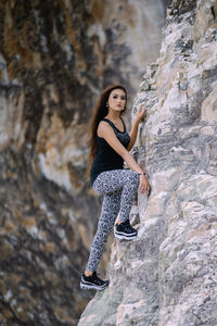 Portrait of young woman climbing on rock