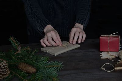 Midsection of person tying string on gift at table