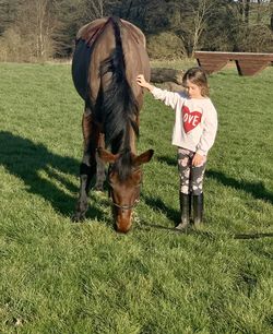 Full length of girl standing with horse on field