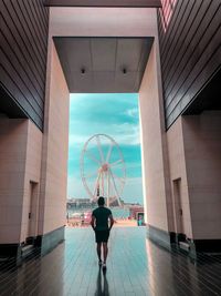 Rear view of woman walking on street amidst buildings in city