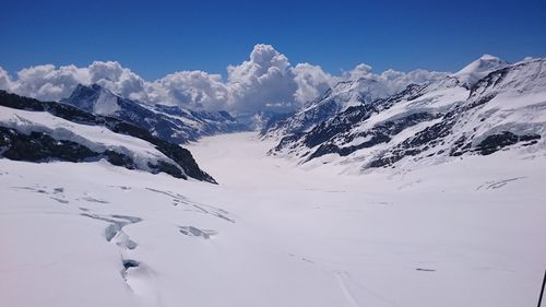 Scenic view of snow covered mountains against blue sky