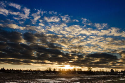 Low angle view of dramatic sky over silhouette landscape