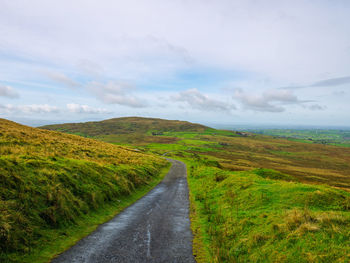 Road amidst green landscape against sky